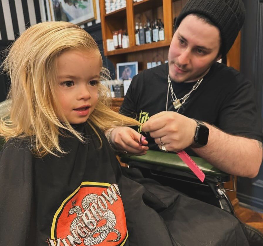 A Little Girl is Getting Her Hair Cut by a Man Wearing a Kangaroo Shirt — Connolly & Co Barbers In Robina, QLD