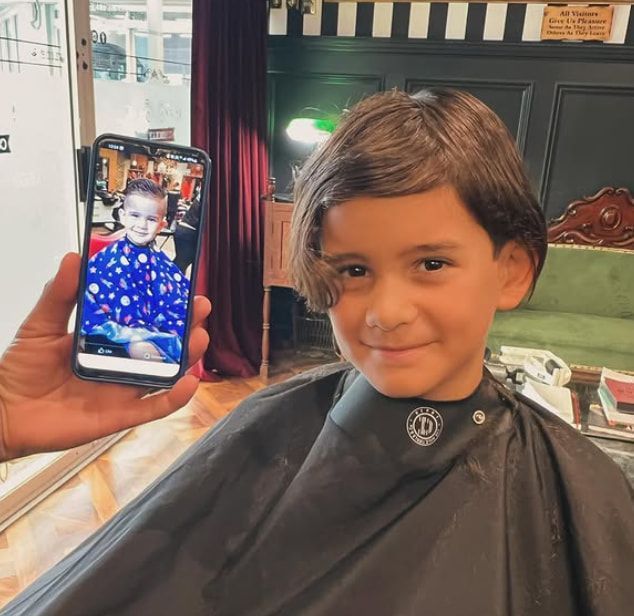 A Person is Holding a Cell Phone With a Picture of a Child on It — Connolly & Co Barbers In Robina, QLD