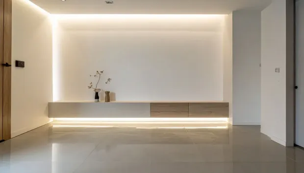 Minimalist empty living room with warm recessed lighting, glossy floor, and a long low console shelf