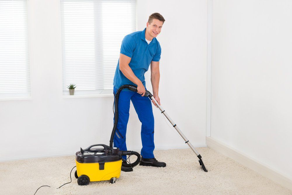 Man Cleaning the Carpet using Vacuum Cleaner — About Us in Bundaberg, QLD