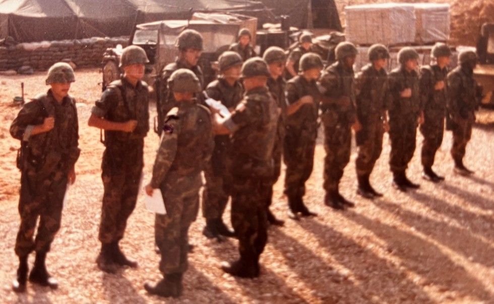 A group of soldiers are standing in a line in the dirt