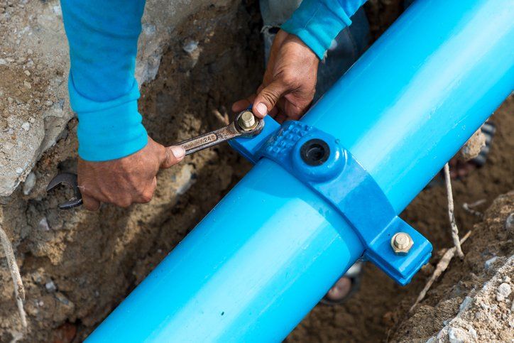 Man using a large wrench on water pipes