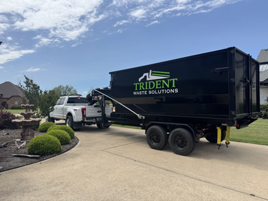 A green dumpster is sitting in a warehouse next to a truck.