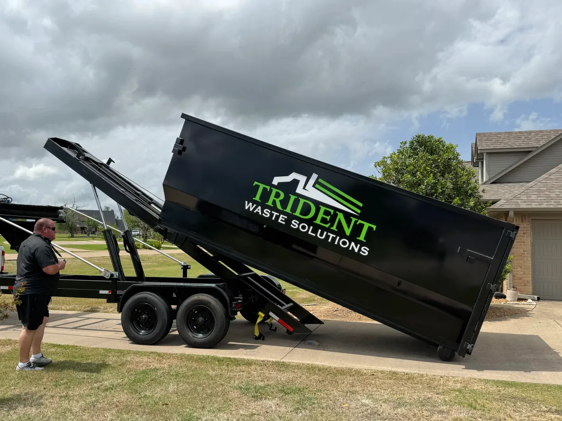 A green dumpster truck is parked on the side of the road.