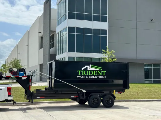 A green dumpster is parked in front of a building.