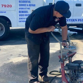 A person operates a concrete grinder next to a truck. The truck has 