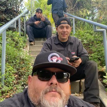 Plumber uses an inspection camera on pipes in a room. Copper pipes, tool case, and a calendar are present.