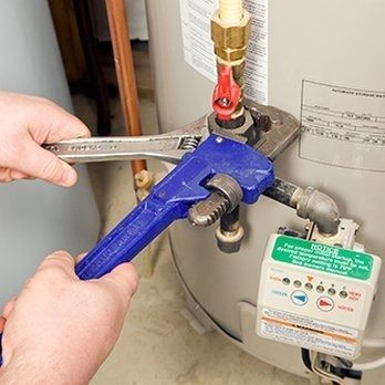Person using wrenches to work on water heater valve.