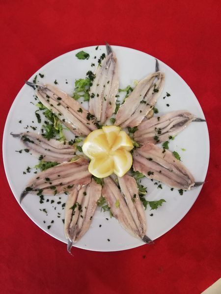 Un piatto bianco con sopra delle acciughe e una fetta di limone