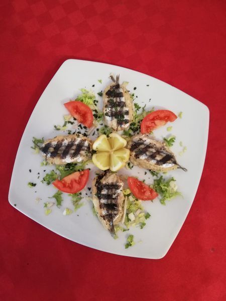 Un piatto bianco condito con pesce, pomodori e lattuga