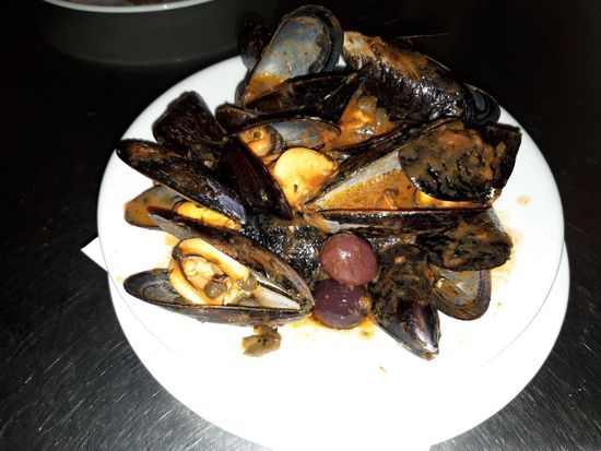 Un piatto bianco con sopra cozze e olive su un tavolo