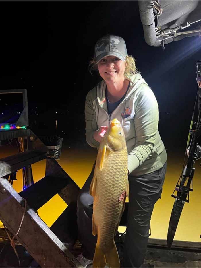 A woman is holding a large fish in her hands