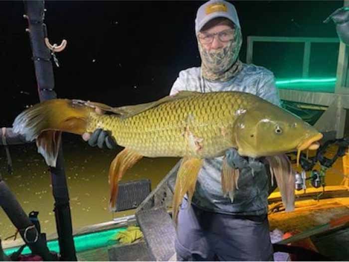A man is holding a large fish in his hands.