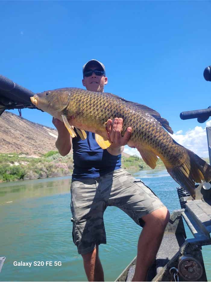 A man is holding a large fish on a boat.