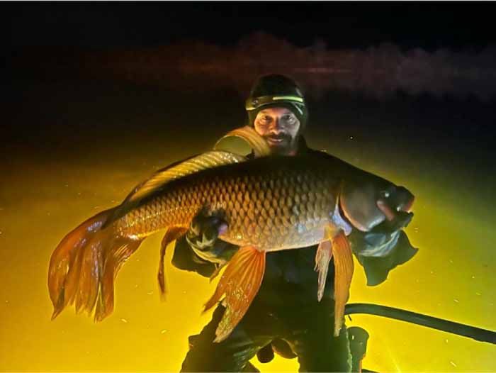 A man is holding a large fish in his hands