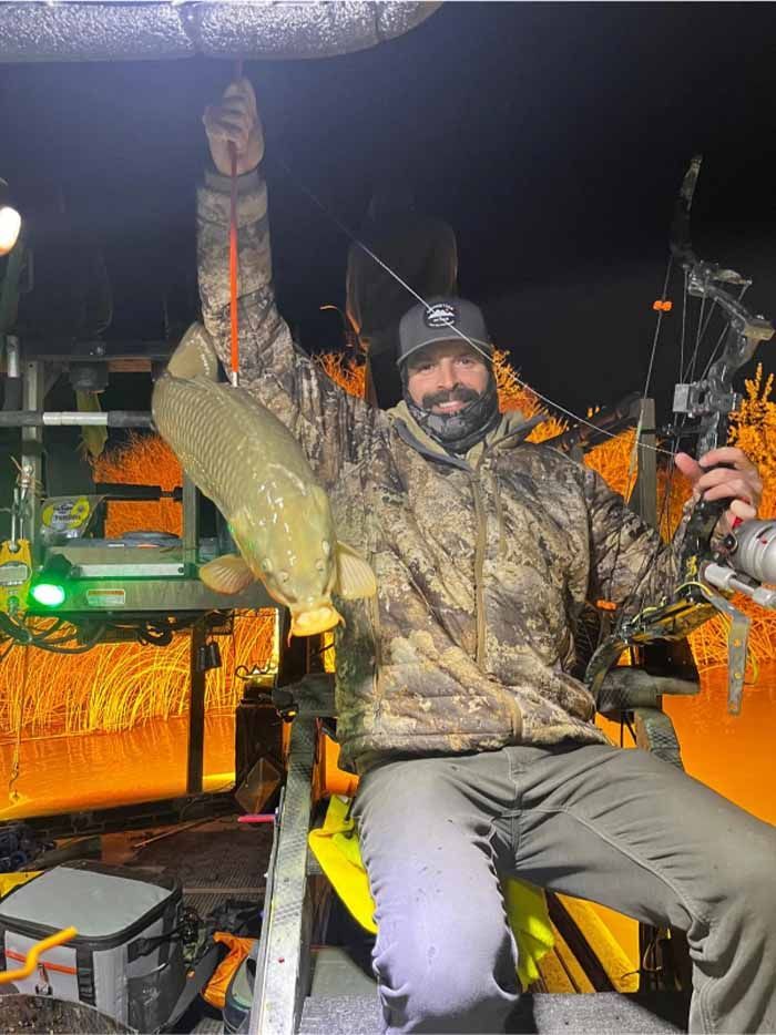 A man is holding a large fish in his hand while sitting on a boat.