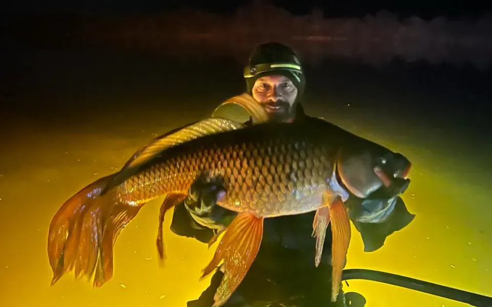 A man is holding a large fish in his hands.