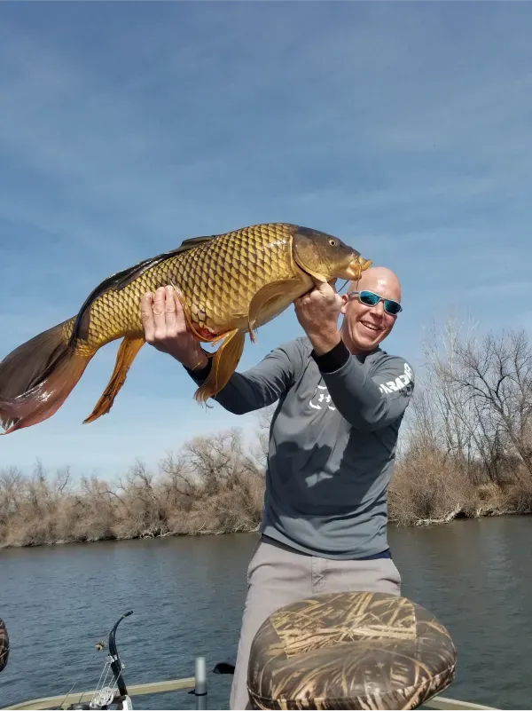 A man on a boat is holding a large fish in his hands