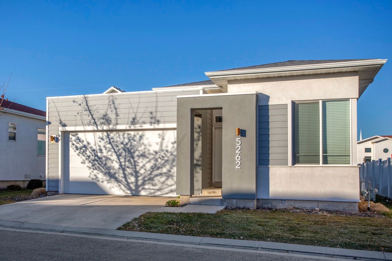 Front exterior of a modern, single-story multifamily unit with a two-car garage and tall address panel.