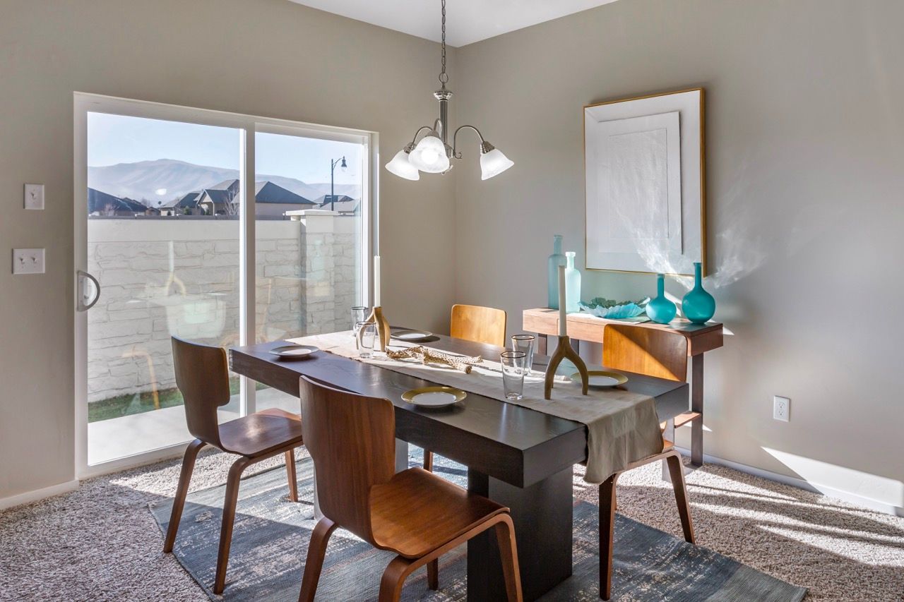Dining area in an apartment with a rectangular table, wooden chairs, and a sliding glass door to the patio.