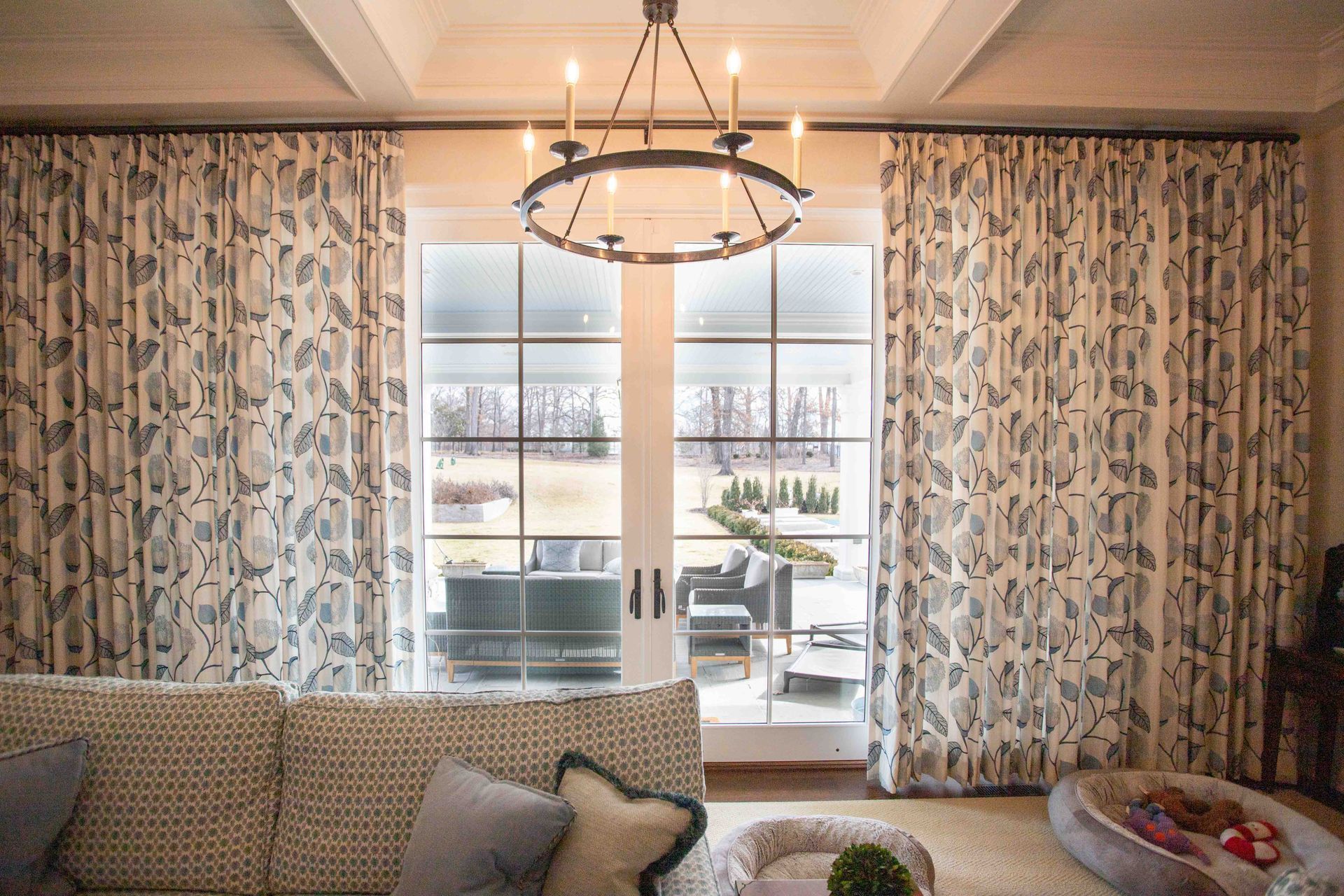 A living room with a couch , chandelier , and sliding glass doors.