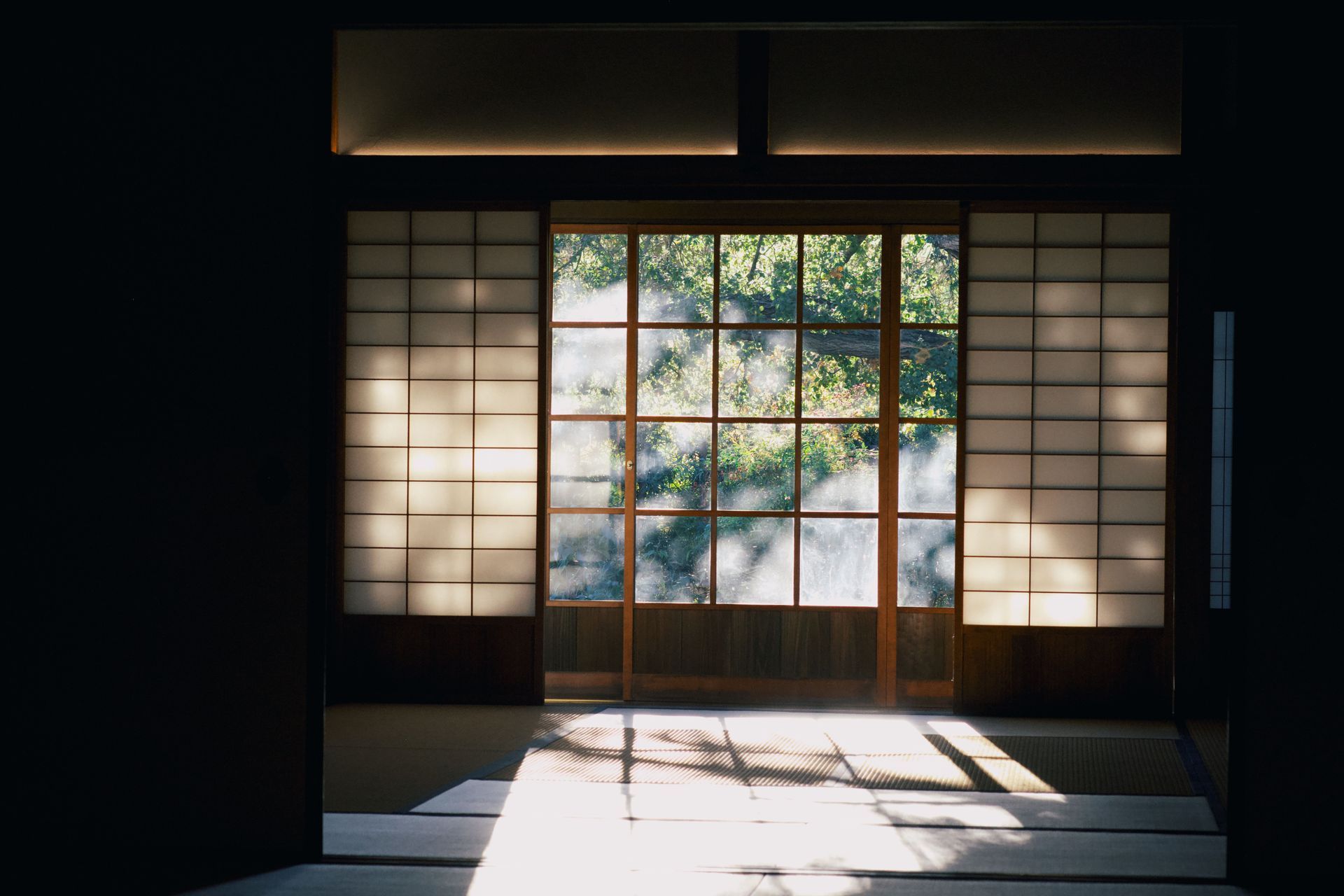 Sunlit Japanese room with shoji screens and garden view through the central window