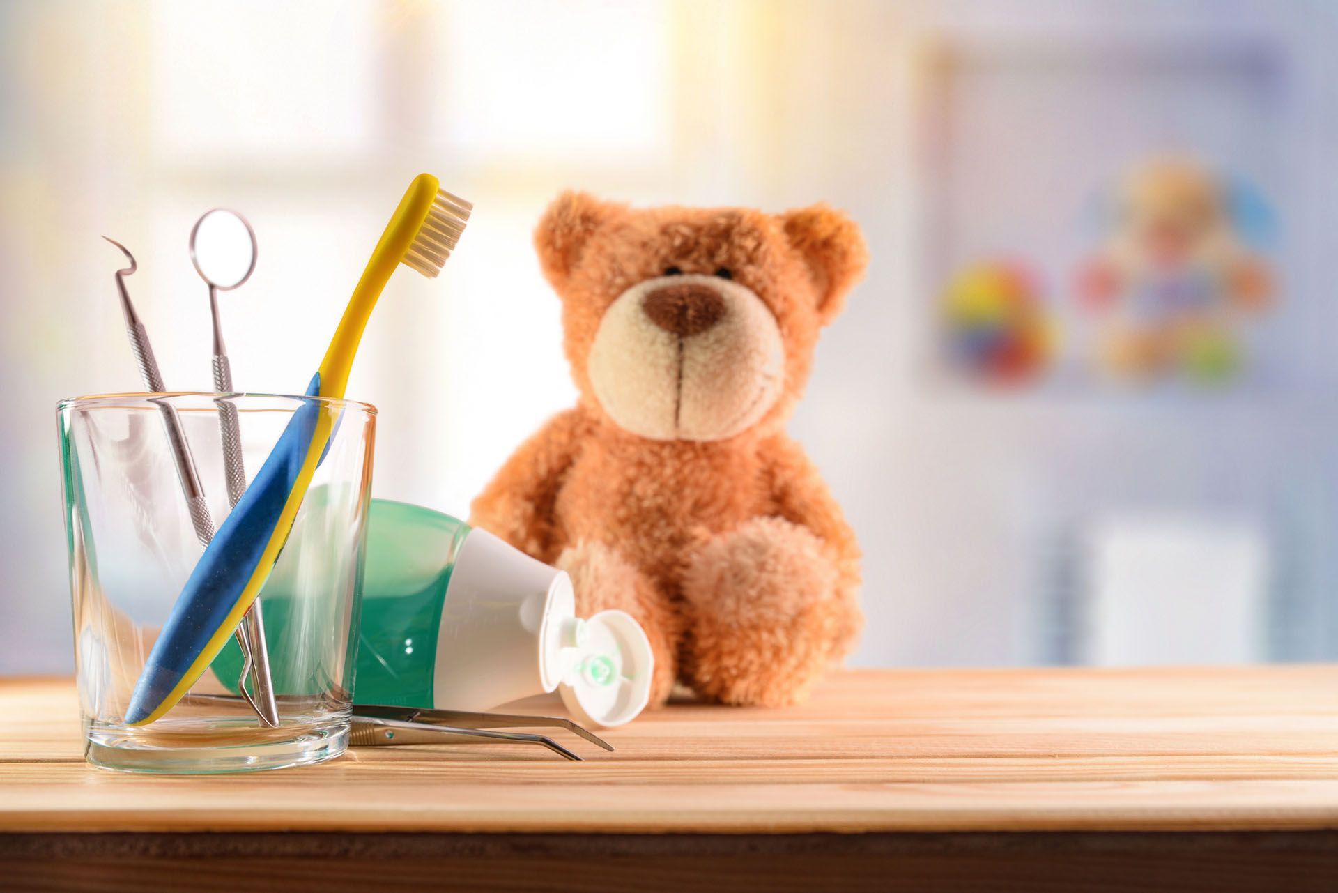 Toothbrush, floss, dental tools, and teddy bear on a table, promoting dental hygiene.