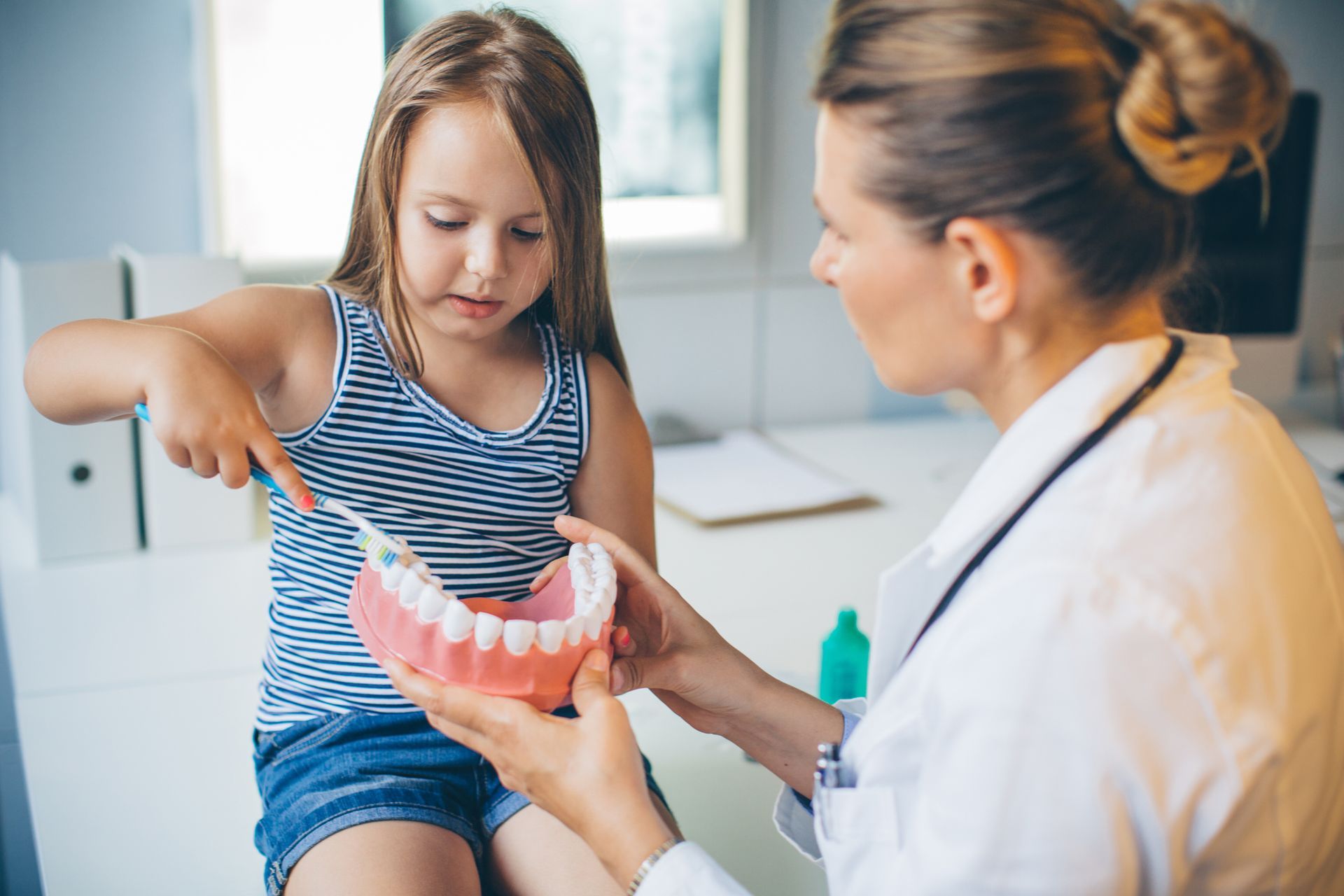 a dentist teaching a child how to brush her teeth a dentist teaching a child how to brush her teeth