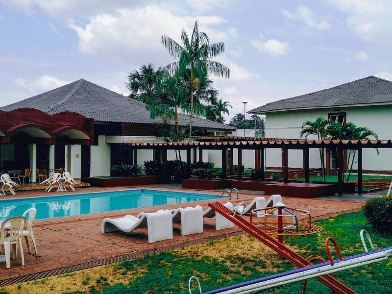 Piscina com cadeiras e hotel ao fundo