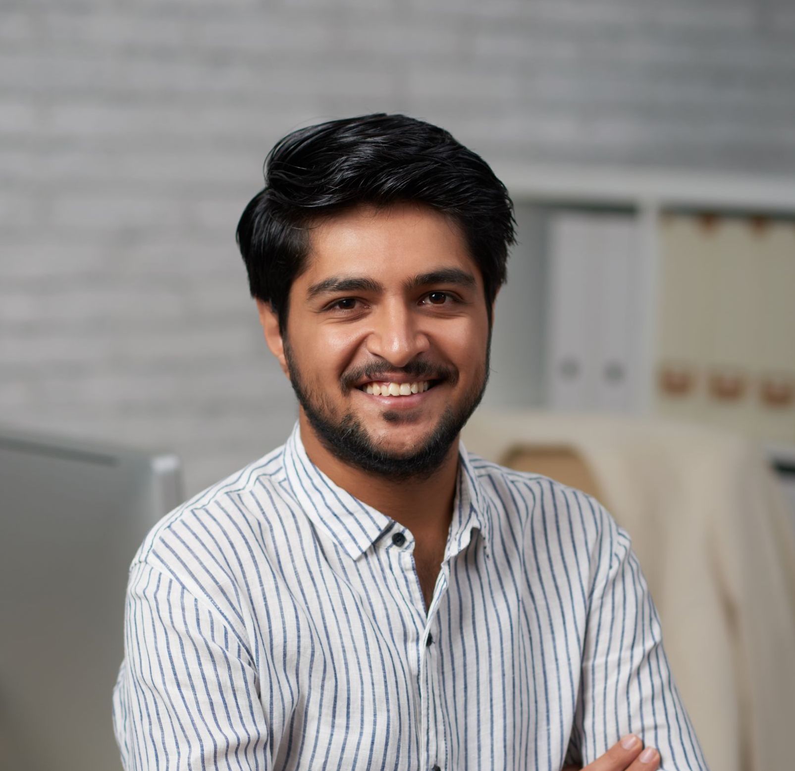A man with a beard is smiling for the camera while wearing a striped shirt.