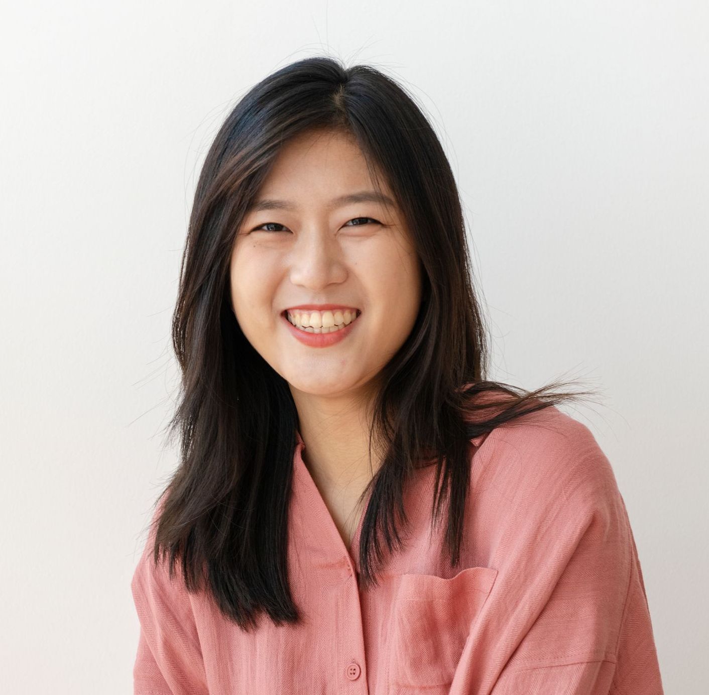 A woman in a pink shirt is smiling for the camera.