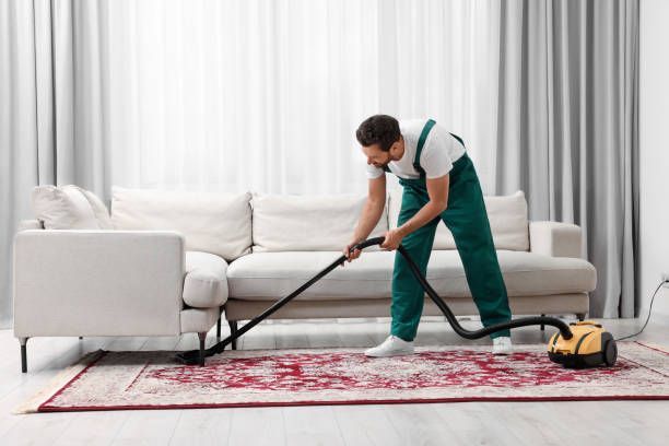 A man vacuuming a living room carpet, showcasing a tidy home and effective carpet cleaning.