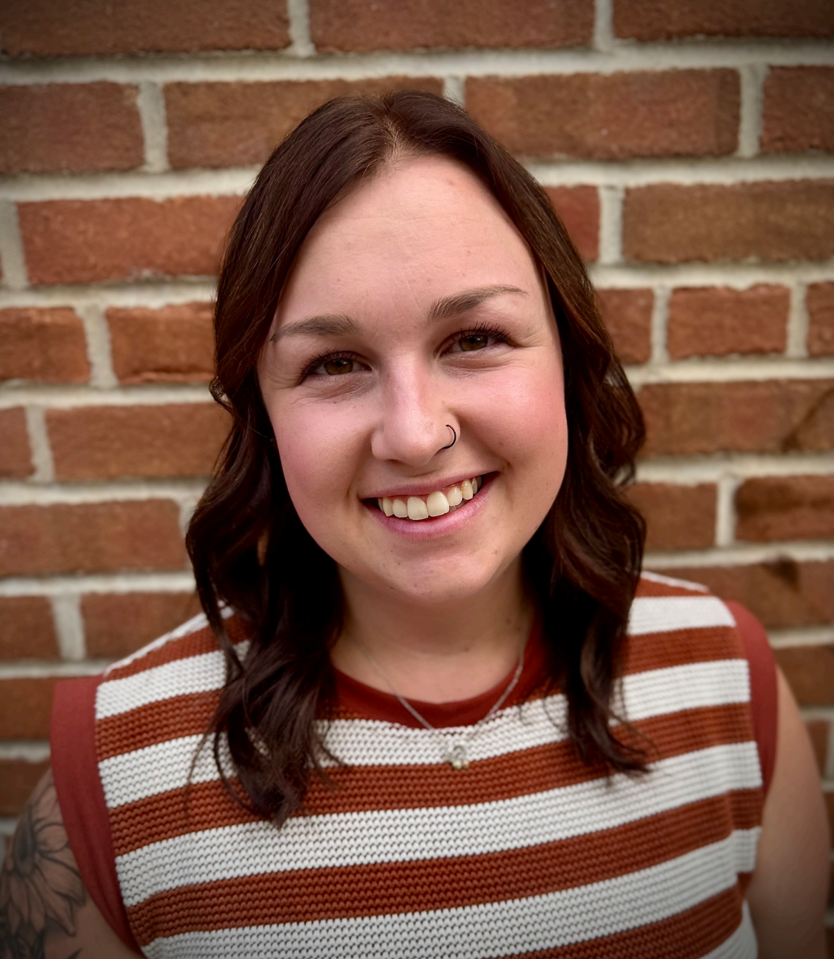 A woman wearing a blue shirt and hoop earrings is smiling in a circle.