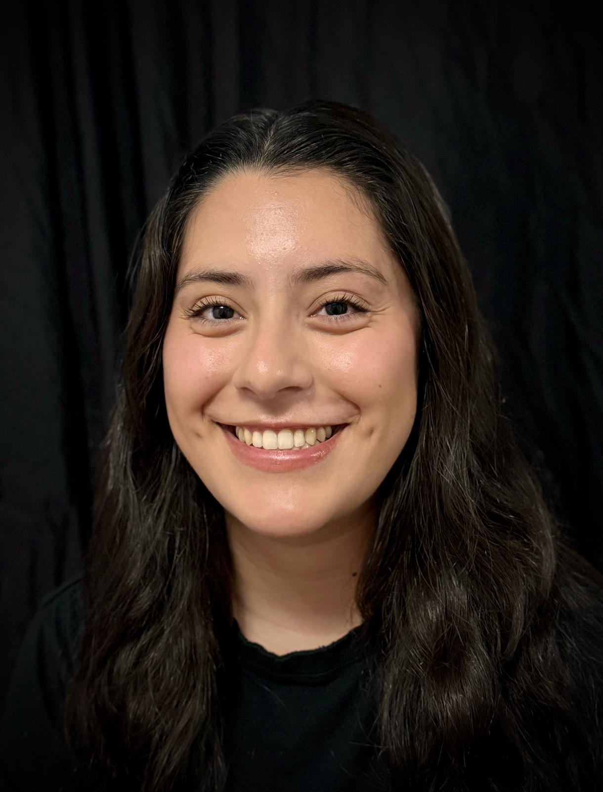 A woman wearing a blue shirt and hoop earrings is smiling in a circle.