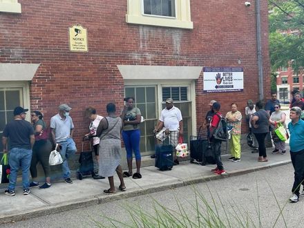 A group of people are standing outside of a brick building.