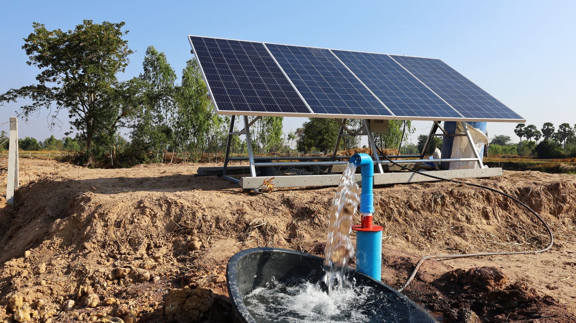 Solar panels powering a water pump, with water flowing into a basin. Outdoors on a sunny day. Solar panels powering a water pump, with water flowing into a basin. Outdoors on a sunny day.