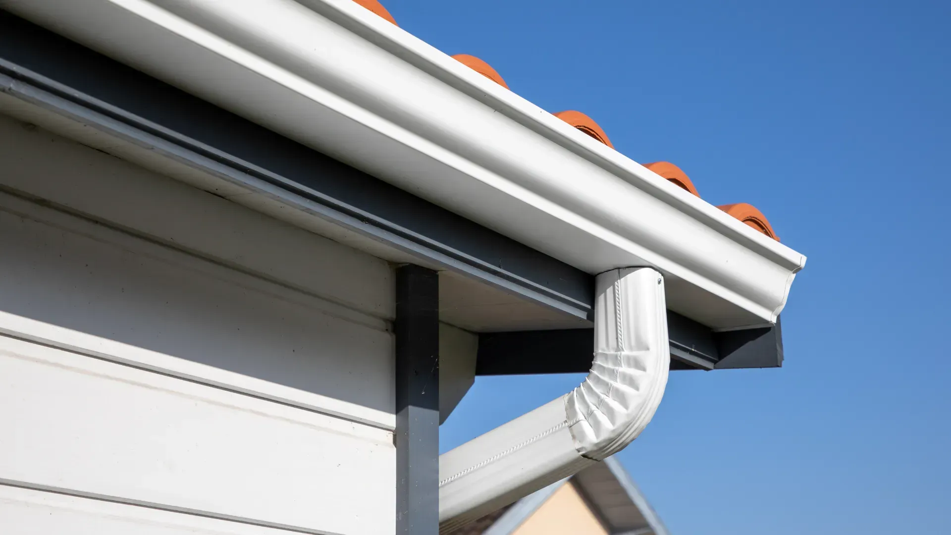 A close up of a gutter on the side of a house.