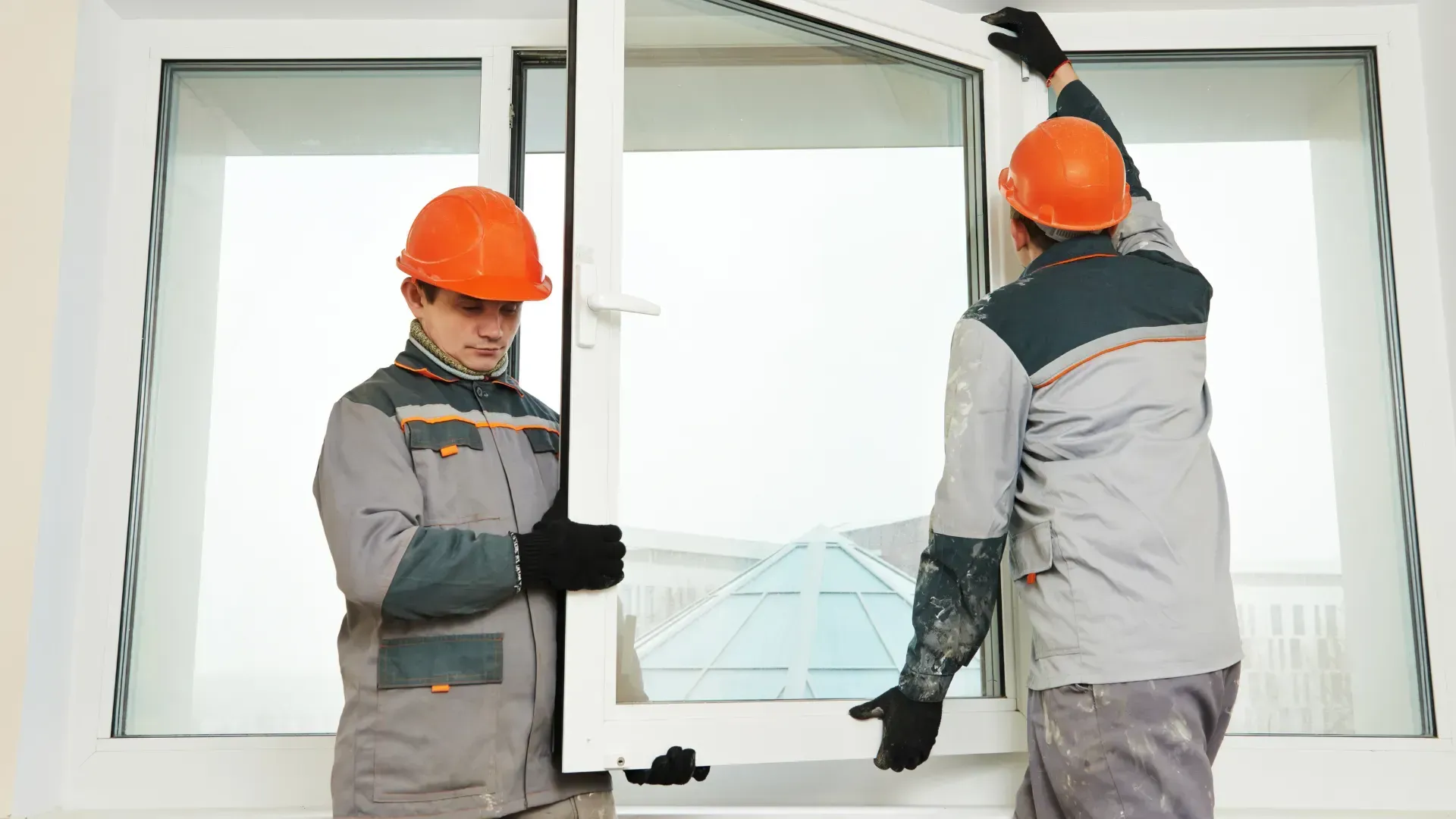 Two men are installing a window in a house.