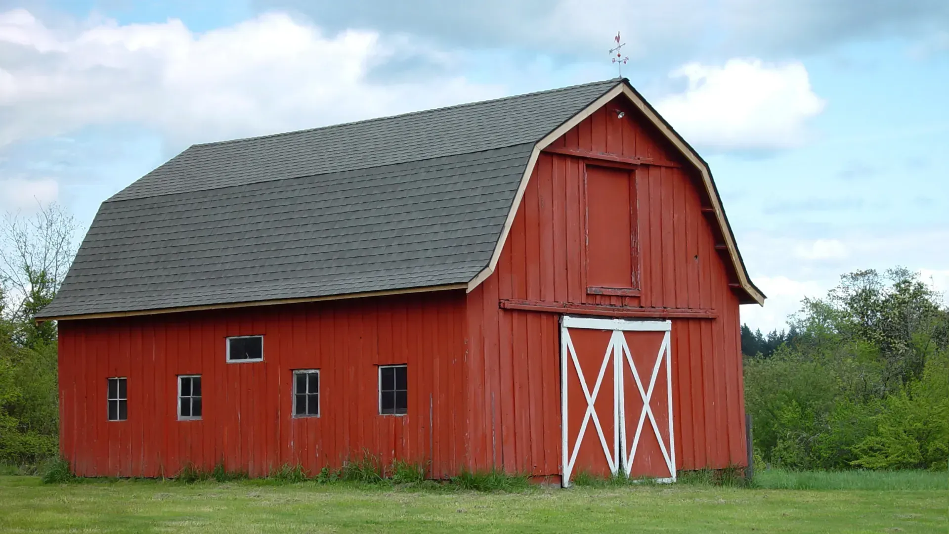 A red barn with a gray roof and white doors