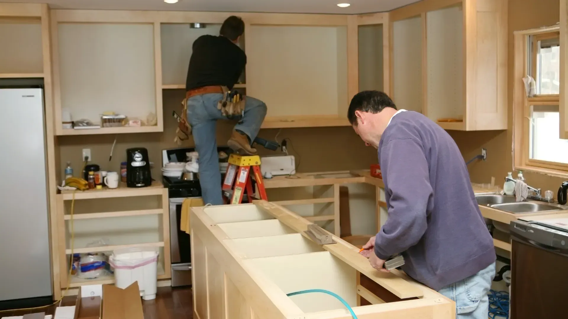 Two men are working on a kitchen remodel.