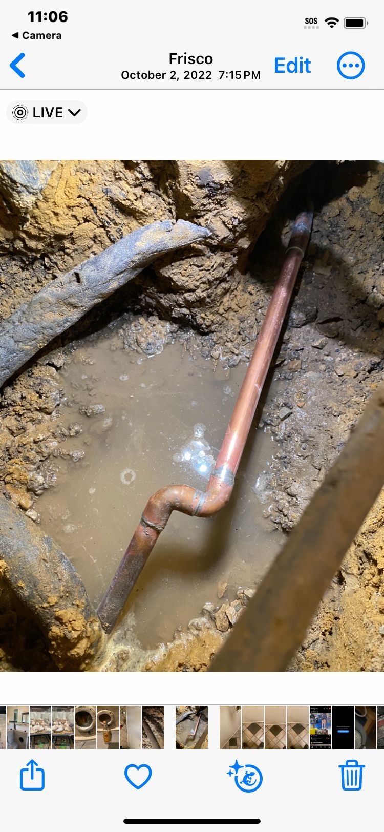 A copper pipe is exposed in a trench filled with water.