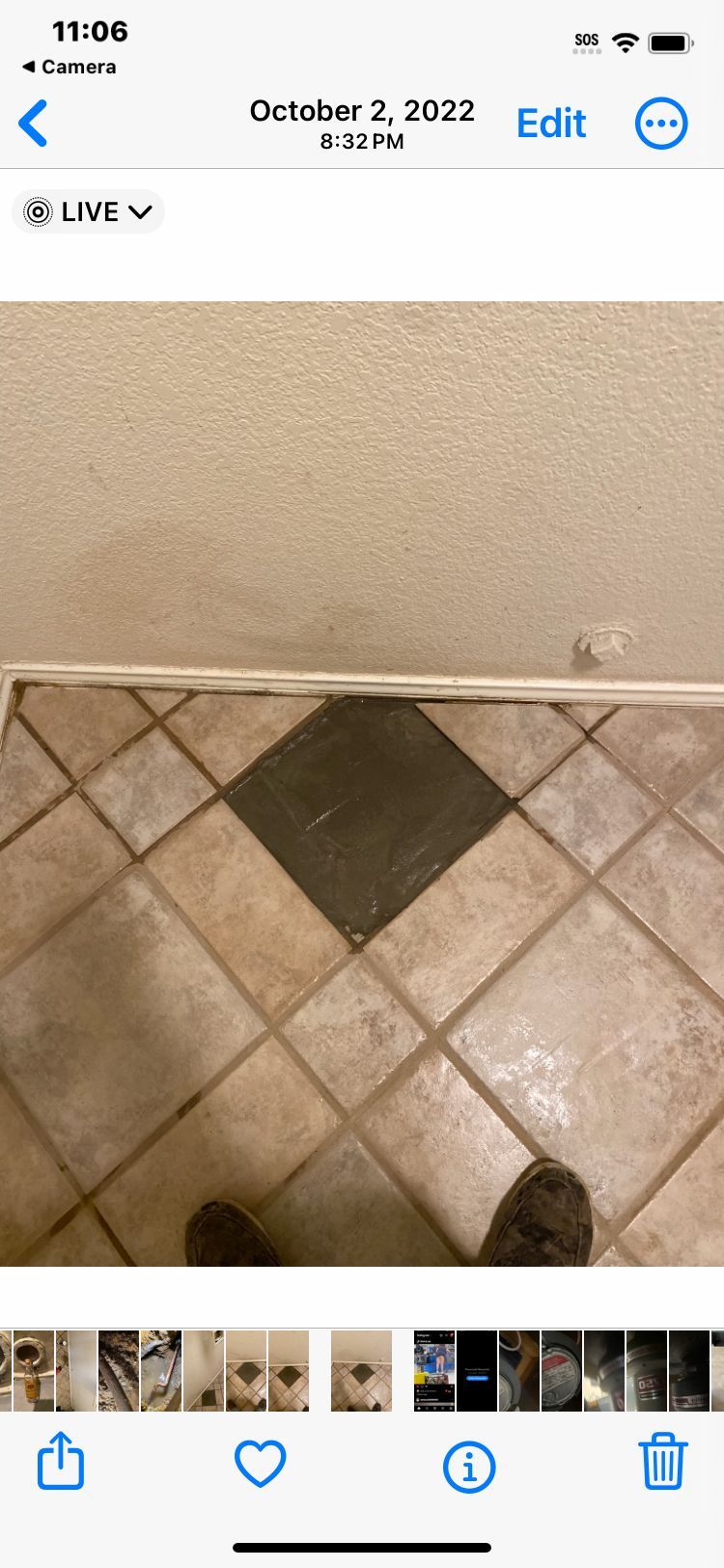 Tiled floor with a dark diamond-shaped tile. Beige wall above the floor. A person’s feet are visible.