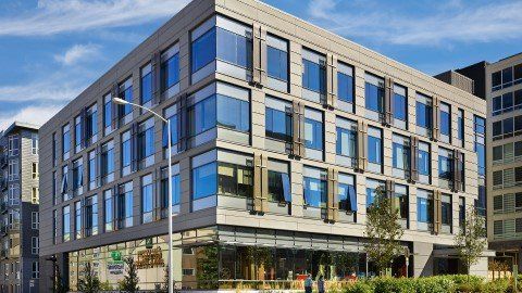 concrete multi-story building in urban setting with large glass windows with blue sky