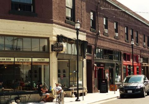multi-story red and white painted brick historic building in urban setting on street corner with coffee shop, outdoor seating and customers