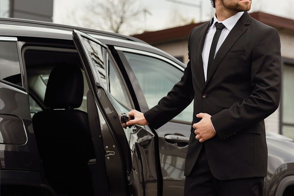 Personen und Objektschützer im Anzug vor Limousine