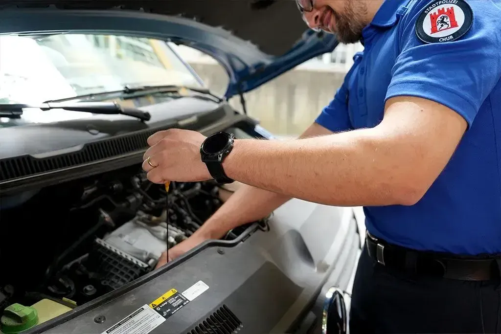 Ein Mitarbeiter der Stadtpolizei Chur schaut unter die Motorhaube eines Autos.