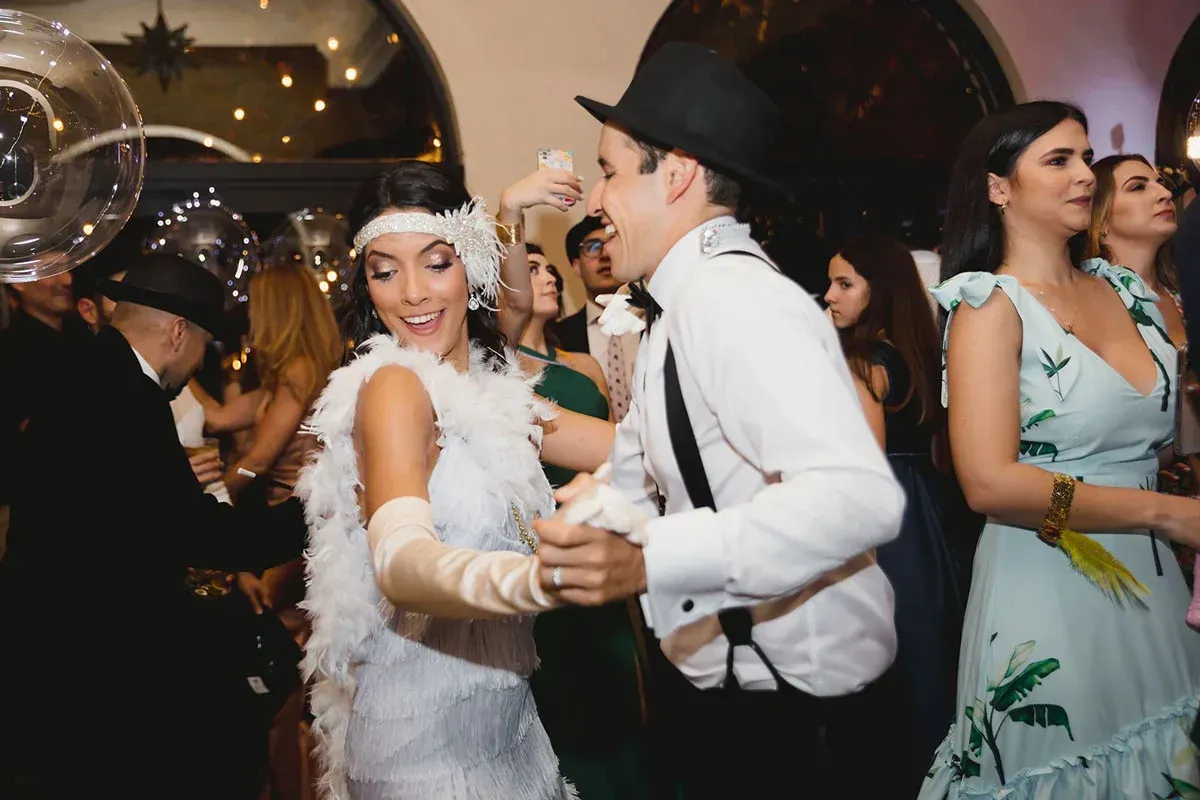 Couple dancing in formal attire, woman in white flapper dress, man in suit. 