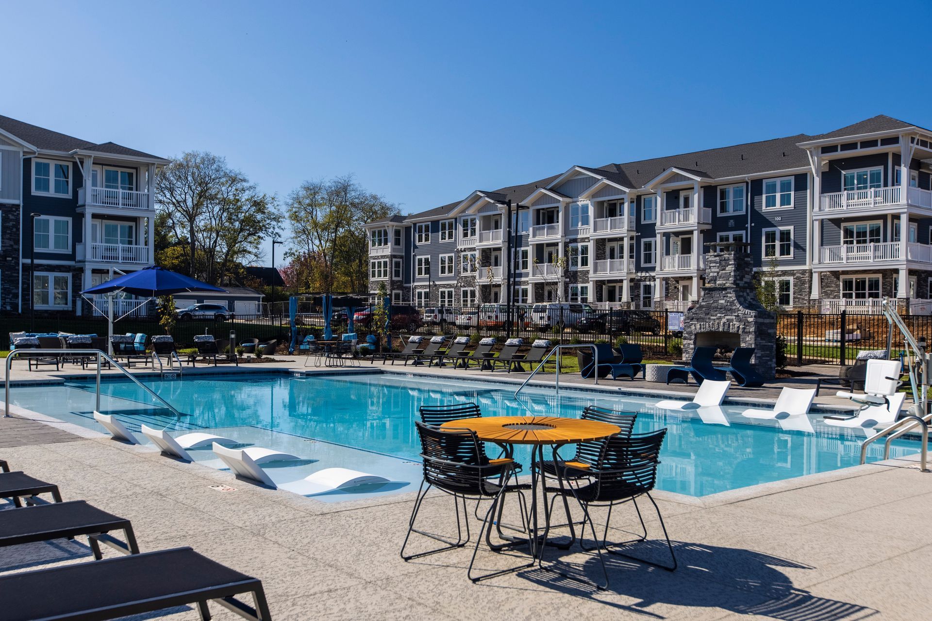 A large swimming pool with a table and chairs in front of a building.