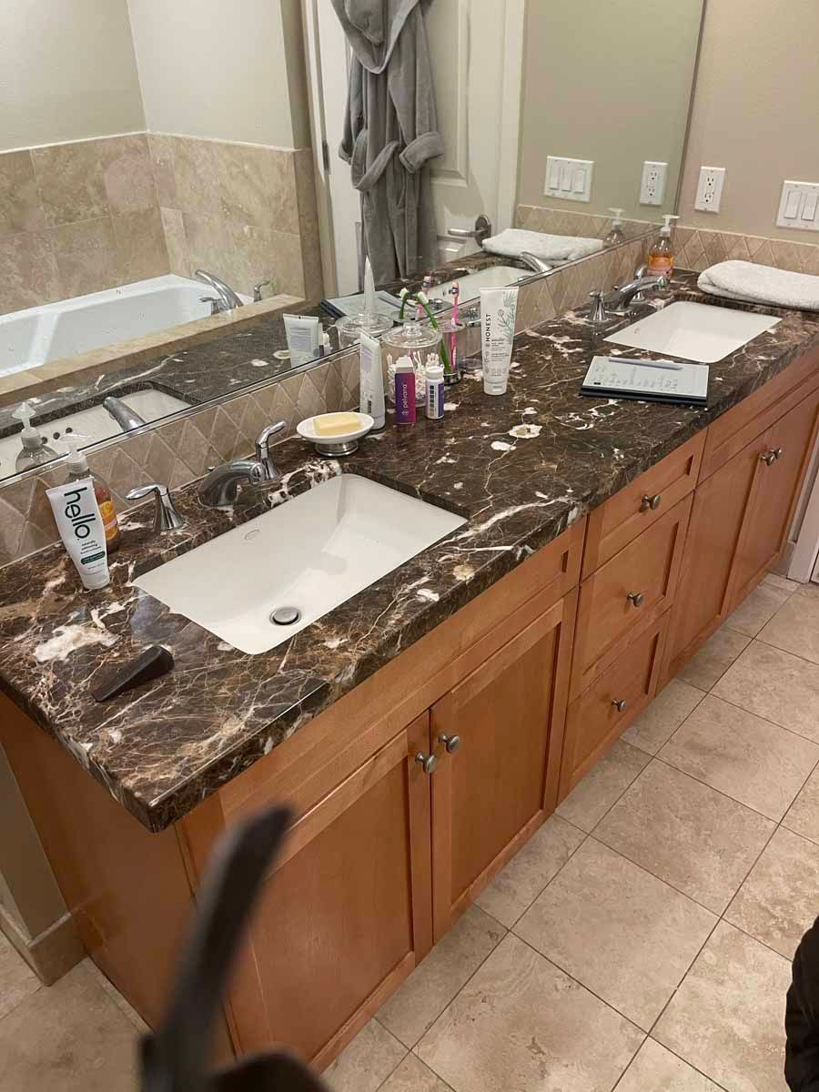 A bathroom with two sinks , a tub and a mirror.