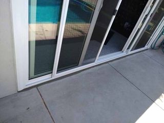 A sliding glass door is open to a patio with a pool in the background.